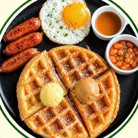 Waffles with butter, sausages, a fried egg, beans and syrup.