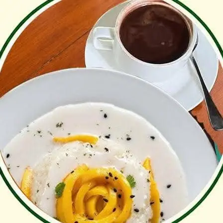Sticky rice in coconut cream with mango slices and a cup of hot chocolate.