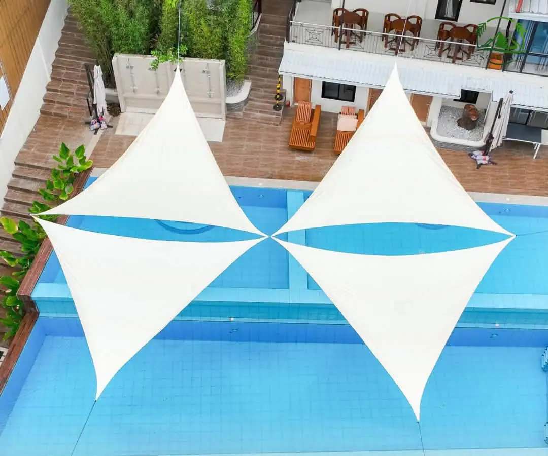 The pool from above, with two white shade sails stretched over the water.